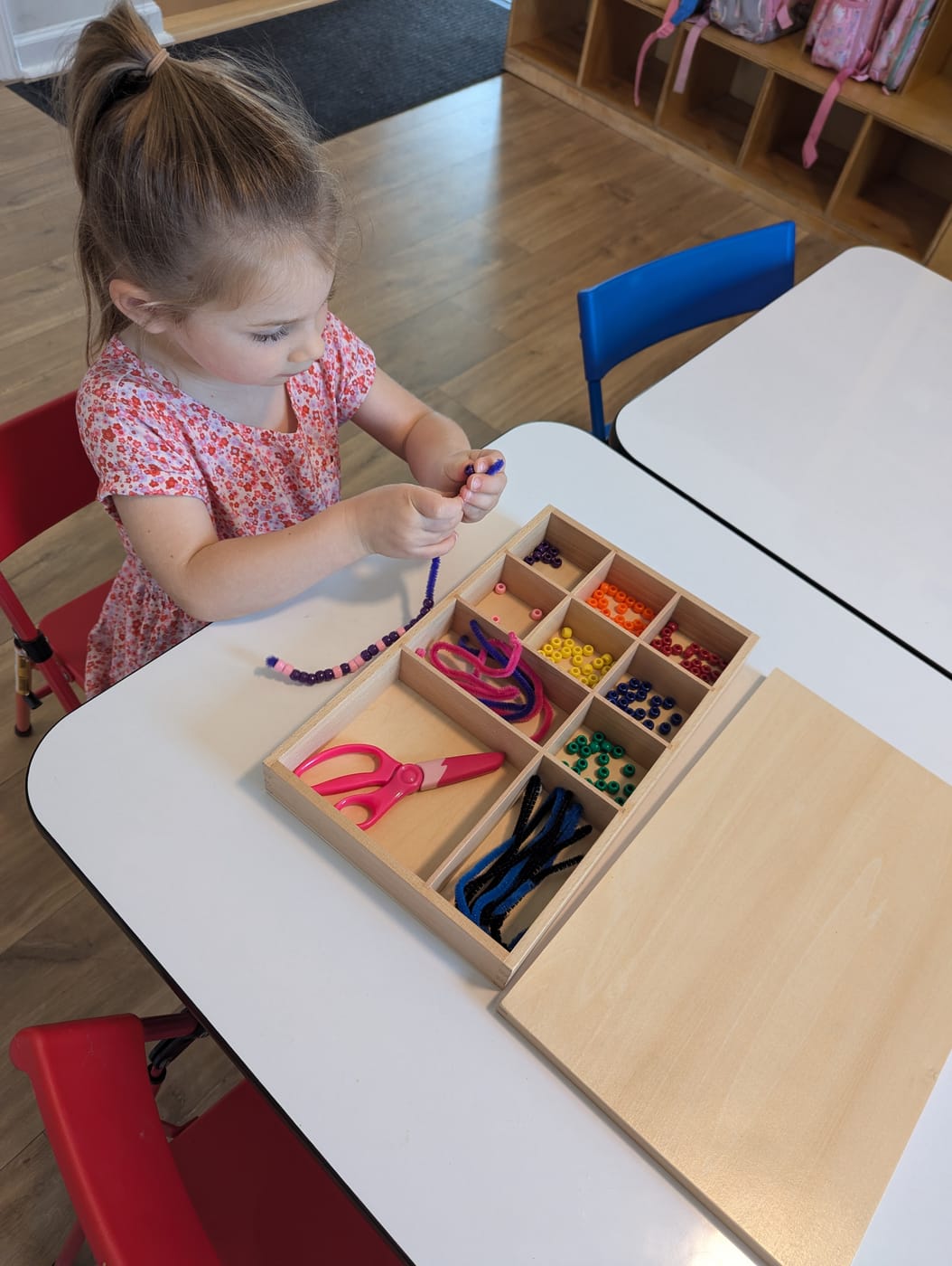 A girl threading beads onto a pipe cleaner